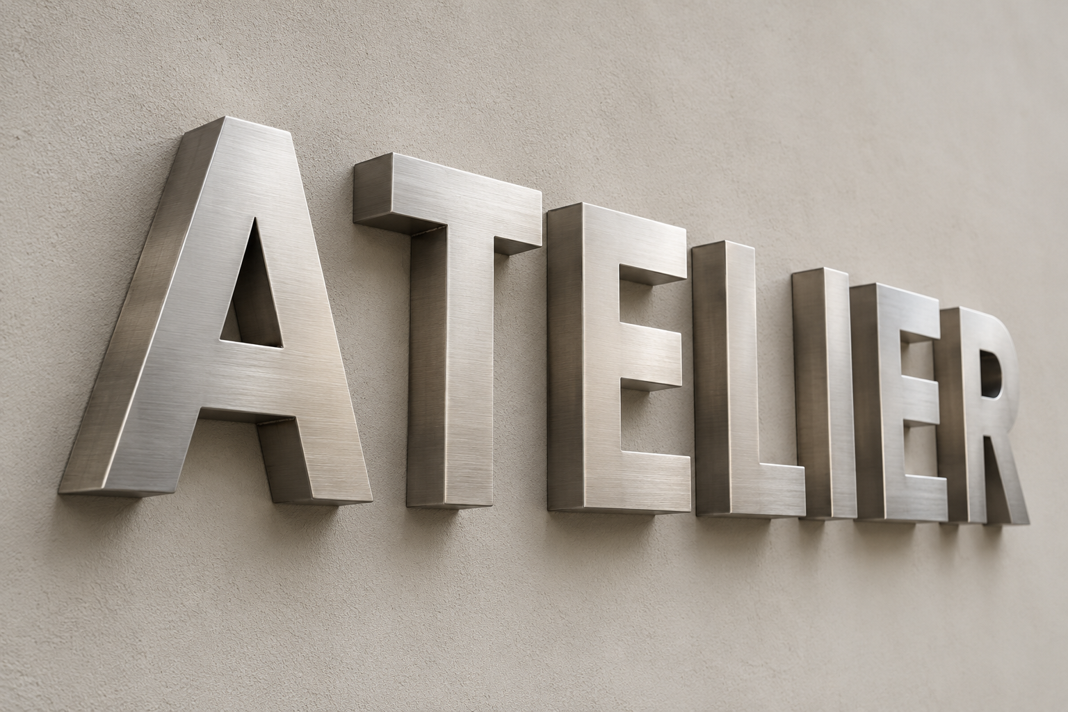 Lettres boîtiers en acier satiné formant ATELIER en relief sur un mur clair